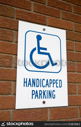 A handicapped parking sign on a brick wall