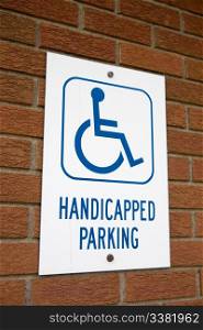 A handicapped parking sign on a brick wall