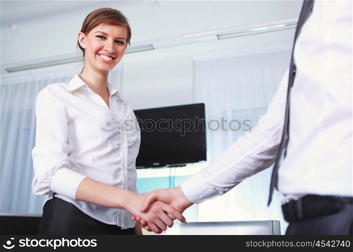 a handshake by a young businesswoman in office