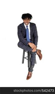 A handsome black man in a suit sitting on a chair, relaxing, with fussy black hair looking at camera, isolated for white background
