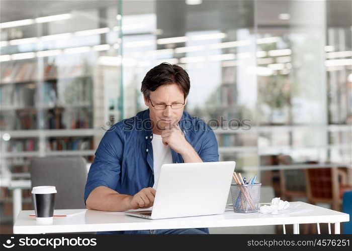 A handsome businessman working on a laptop in his office