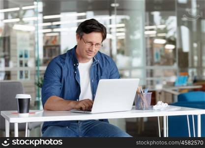 A handsome businessman working on a laptop in his office