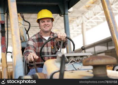 A handsome construction worker driving a bulldozer on a construction site.