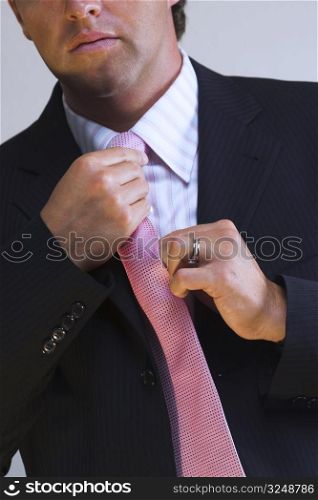 A handsome man sets right his trendy tie.