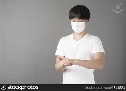 A handsome man with surgical mask is using alcohol hand sanitizer