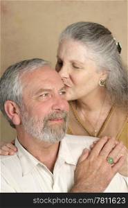 A handsome mature man getting a kiss from his beautiful wife.
