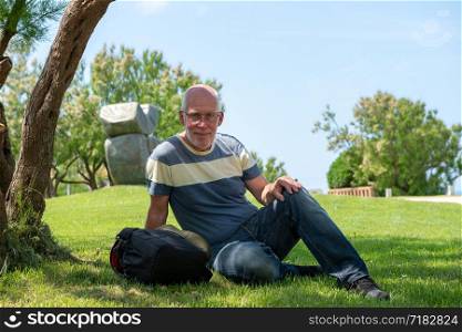 a handsome mature man is resting under a tree