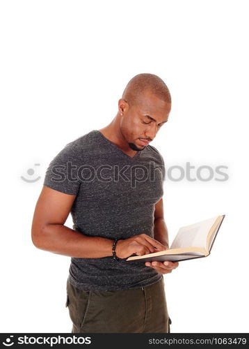 A handsome young African American man standing in the studio isolated for white background reading his book and looking serious