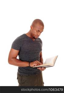 A handsome young African American man standing in the studio isolated for white background reading his book and looking serious