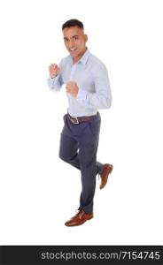 A handsome young man in a blue shirt and dress pants is running in the studio, isolated for white background