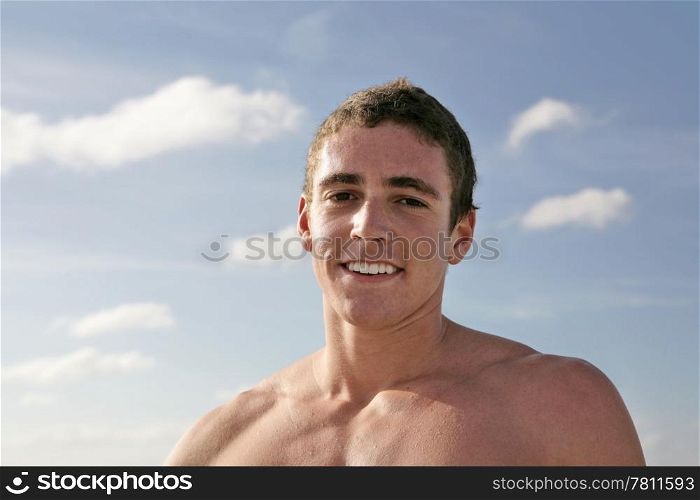 A handsome young man, shirtless against a blue sky.