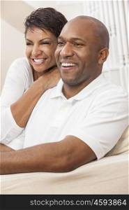 A happy African American man and woman couple with perfect teeth, in their thirties sitting at home