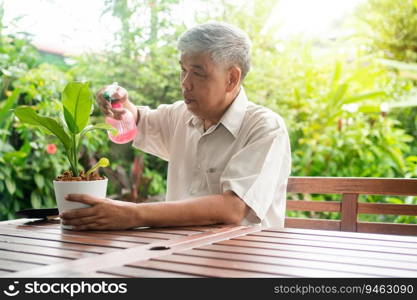 A happy and smiling Asian old elderly man is planting for a hobby after retirement in a home. Concept of a happy lifestyle and good health for seniors.