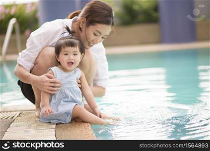 A Happy Asian mother and daughter are enjoy swimming in pool , lifestyle, parenthood, family concept .. A Happy Asian mother and daughter are enjoy swimming in pool , lifestyle, parenthood, family concept