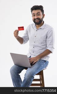 A HAPPY BEARDED MAN SHOWING DEBIT CARD IN FRONT OF CAMERA