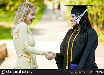 A happy beautiful graduation girl being congratulated by her friend