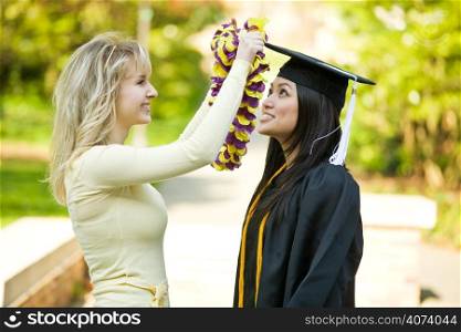A happy beautiful graduation girl being congratulated by her friend