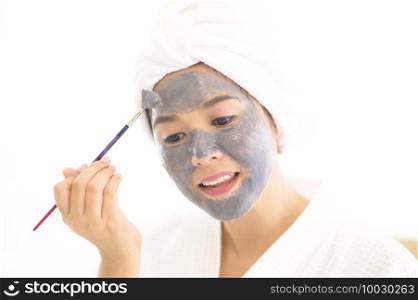 A happy beautiful woman in white bathrobe applying a face mask, skin care and treatment concept. Happy beautiful woman in white bathrobe applying a face mask, skin care and treatment concept