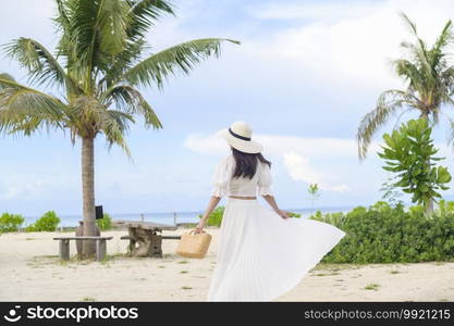 A happy beautiful woman in white dress enjoying and relaxing on the beach, Summer and holidays concept