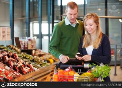A happy couple buying groceries looking at grocery list on phone