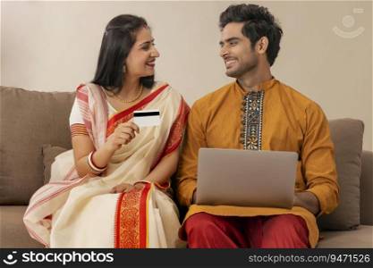A HAPPY COUPLE ENJOYING TIME WITH EACH OTHER WHILE DOING ONLINE TRANSACTIONS