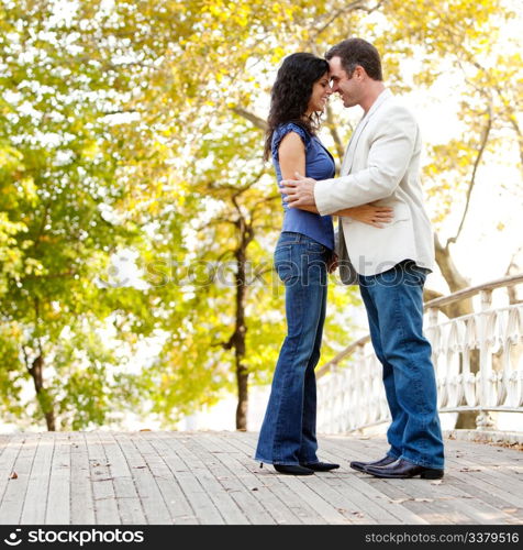 A happy couple in the park looking at the camera and hugging