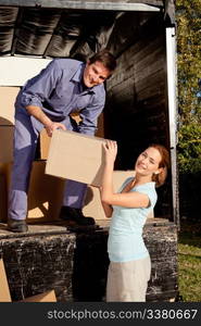 A happy couple moving boxes from a moving truck