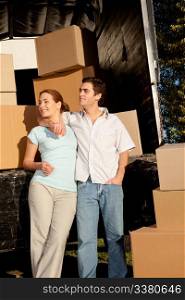 A happy couple with a moving truck and boxes