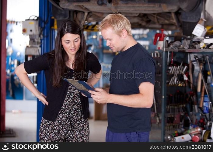 A happy customer looking at the service report in a mechanic shop