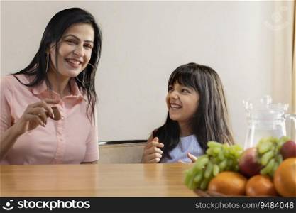 A HAPPY DAUGHTER LOOKING AT MOTHER WHILE EATING COOKIE