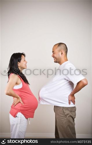 A happy expecting pregnant asian couple facing each other