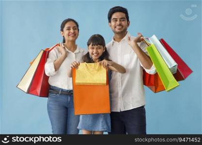 A HAPPY FAMILY ENTHUSIASTICALLY POSING IN FRONT OF CAMERA AFTER SHOPPING