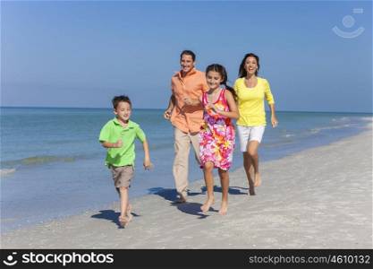 A happy family of mother, father and two children, son and daughter, running and having fun in the sand of a sunny beach