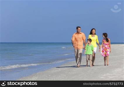 A happy family of mother, father and two children, son and daughter, walking and having fun in the sand of a deserted sunny beach