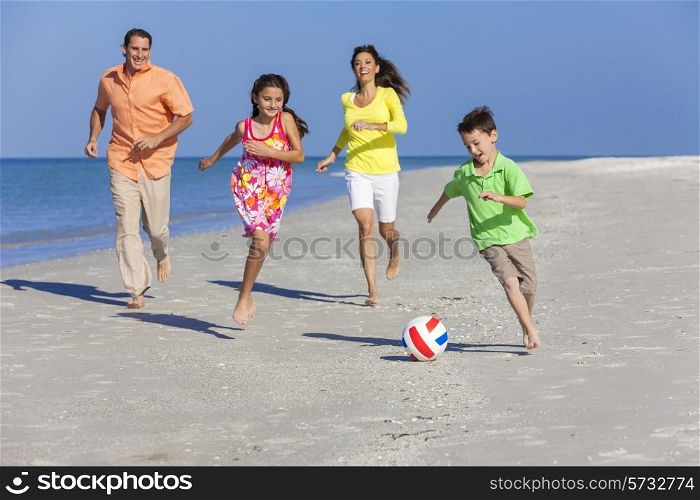A happy family of mother, father and two children, son and daughter, running playing soccer or football in the sand of a sunny beach