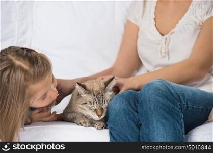 A happy family of two with a cat sitting on sofa and having fun