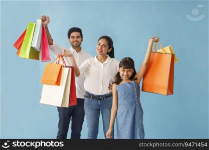 A HAPPY FAMILY PLAYFULLY POSING IN FRONT OF CAMERA WITH SHOPPING BAGS