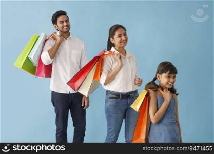 A HAPPY FAMILY PLAYFULLY STANDING WITH SHOPPING BAGS