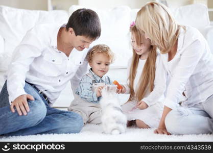 A happy family with children feeding a pet