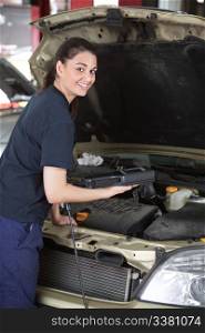 A happy female mechanic looking at the camera using a diagnostic scan tool