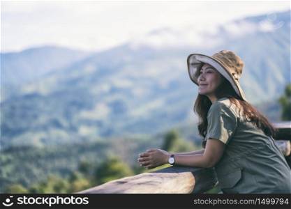 A happy female traveler with a beautiful green mountains landscape on foggy day