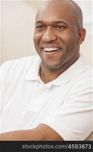 A happy handsome African American man with perfect teeth in his thirties sitting at home