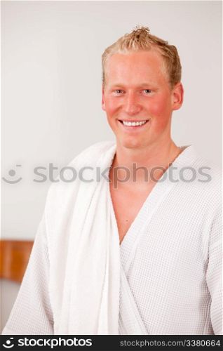 A happy handsome bonde man in a bathrobe smiling and looking at the camera