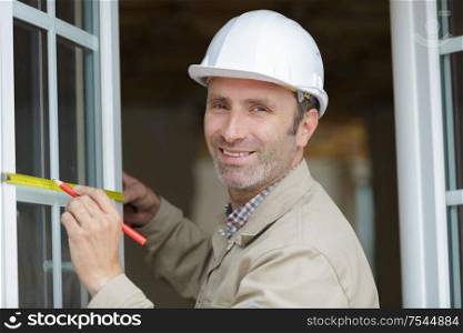 a happy male worker measuring window