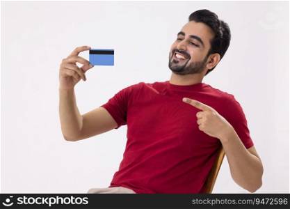 A HAPPY MAN POINTING TOWARDS DEBIT CARD IN HAND
