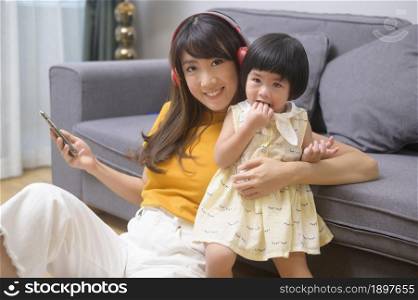 A happy mom and daughter listening to music and relaxing at home. Happy mom and daughter listening to music and relaxing at home