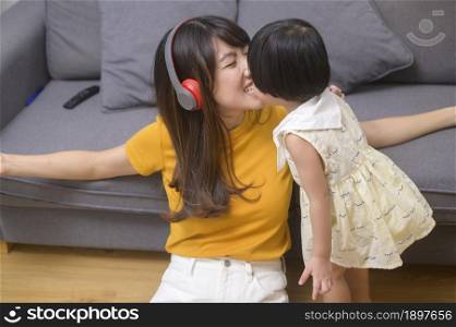 A happy mom and daughter listening to music and relaxing at home. Happy mom and daughter listening to music and relaxing at home