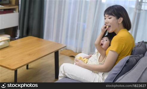 A happy mom and daughter watching movie and relaxing at home. Happy mom and daughter watching movie and relaxing at home