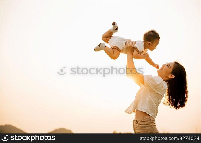 A happy mother holds her baby up in the air in the park, while the child enjoys a moment of playful freedom and joy. Love and family captured in a photograph