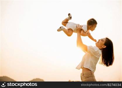 A happy mother holds her baby up in the air in the park, while the child enjoys a moment of playful freedom and joy. Love and family captured in a photograph